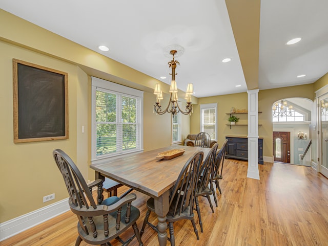 dining area with light wood-type flooring, a wealth of natural light, and a chandelier