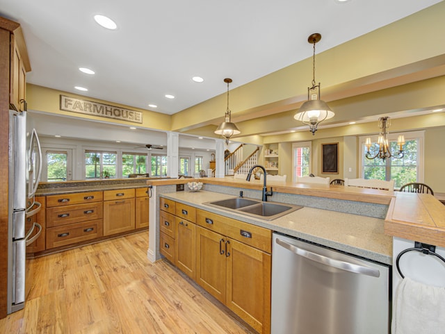 kitchen featuring an inviting chandelier, decorative light fixtures, light hardwood / wood-style flooring, appliances with stainless steel finishes, and sink