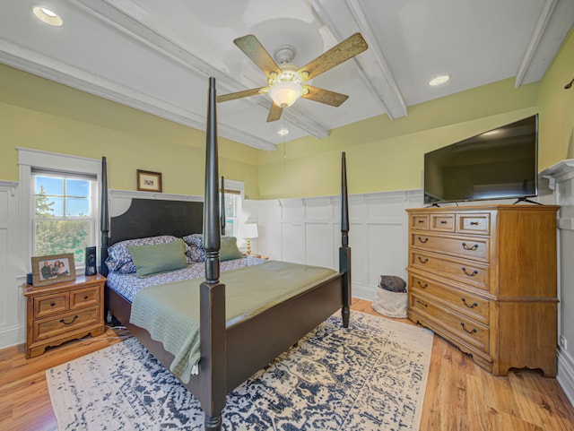 bedroom with light hardwood / wood-style flooring, ceiling fan, and beamed ceiling