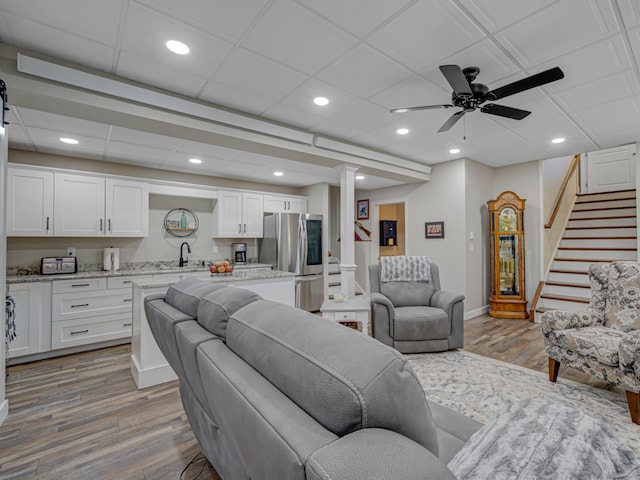 living room with a drop ceiling, sink, ceiling fan, ornate columns, and light hardwood / wood-style floors