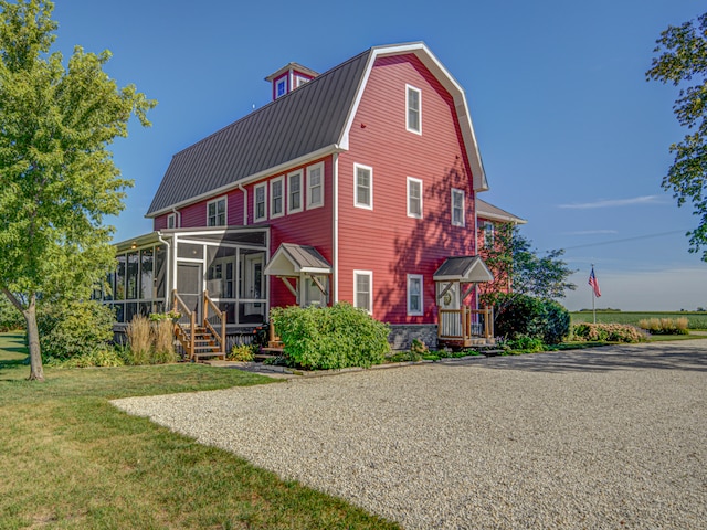 back of property featuring a lawn and a sunroom