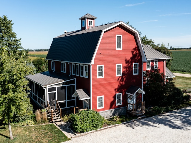 back of property featuring a lawn, a rural view, and a sunroom