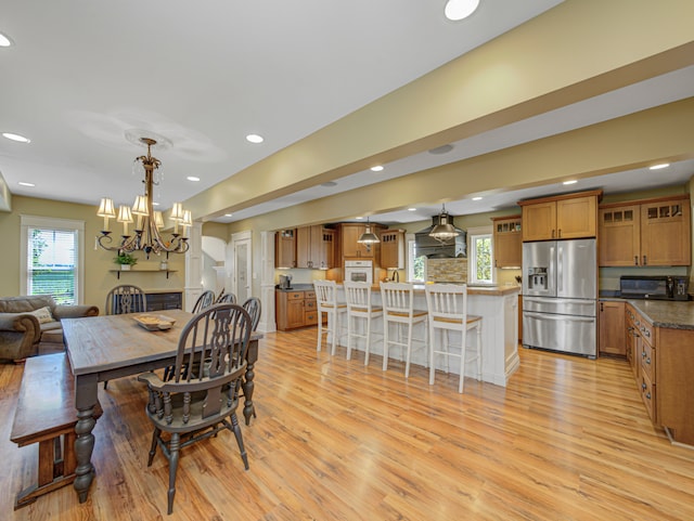 dining space featuring a wealth of natural light, an inviting chandelier, and light hardwood / wood-style flooring