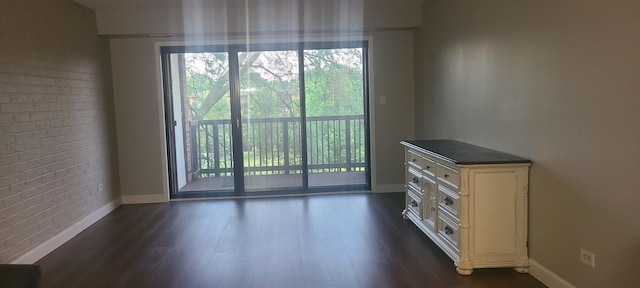 unfurnished room featuring dark wood-type flooring and brick wall