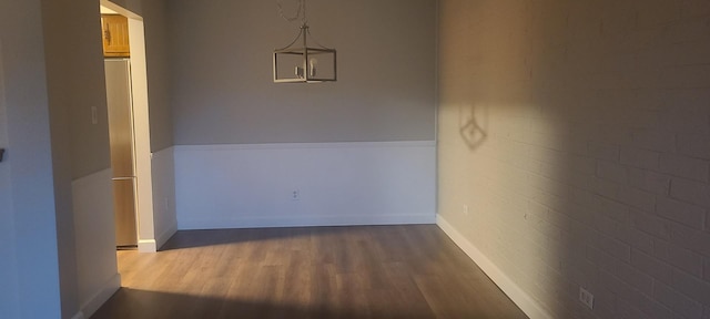 unfurnished dining area featuring dark wood-type flooring and brick wall