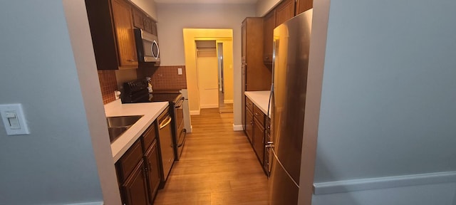 kitchen featuring decorative backsplash, sink, stainless steel appliances, and light hardwood / wood-style flooring