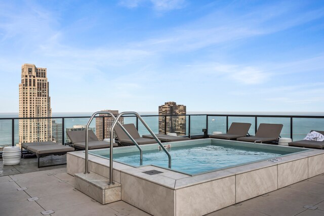 view of pool with an in ground hot tub and a water view