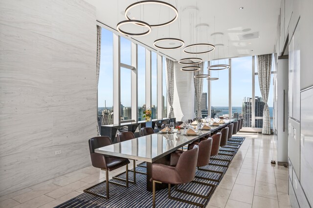 dining space with tile walls, a wealth of natural light, an inviting chandelier, and a wall of windows