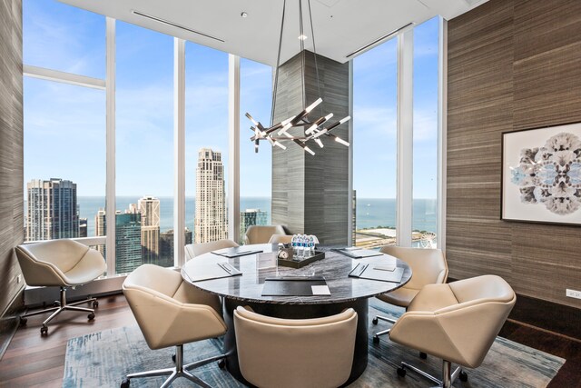 dining space with a notable chandelier, expansive windows, wood-type flooring, and a water view