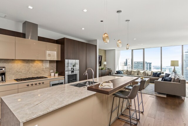 kitchen with light stone counters, dark hardwood / wood-style floors, a center island with sink, and sink