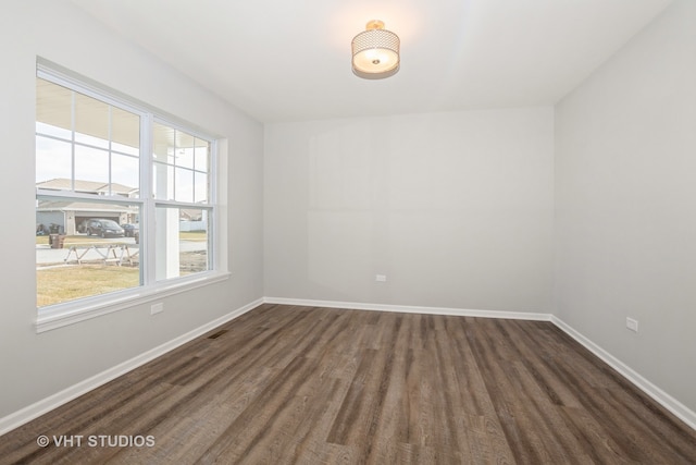 empty room with dark hardwood / wood-style flooring and a wealth of natural light