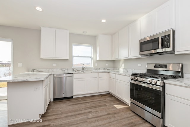 kitchen with appliances with stainless steel finishes, white cabinetry, and light hardwood / wood-style floors