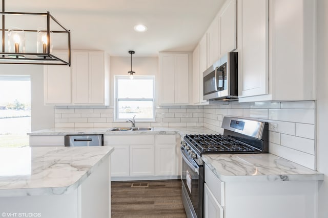 kitchen with appliances with stainless steel finishes, white cabinetry, dark hardwood / wood-style floors, sink, and decorative light fixtures