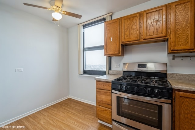 kitchen with ceiling fan, light wood-type flooring, and stainless steel range with gas cooktop