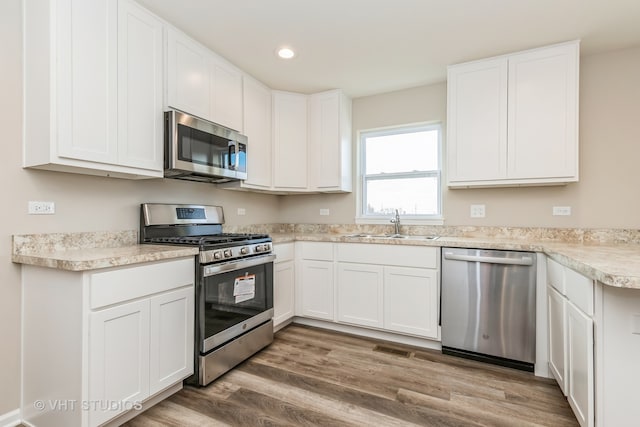 kitchen featuring hardwood / wood-style flooring, appliances with stainless steel finishes, sink, and white cabinets