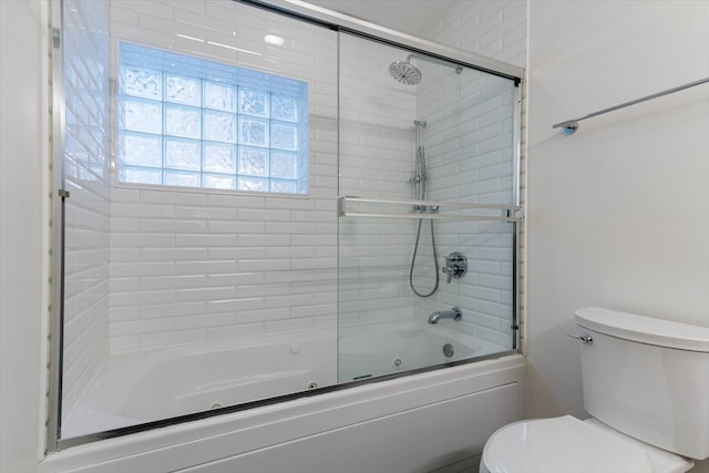 bathroom featuring shower / bath combination with glass door, toilet, and a wealth of natural light