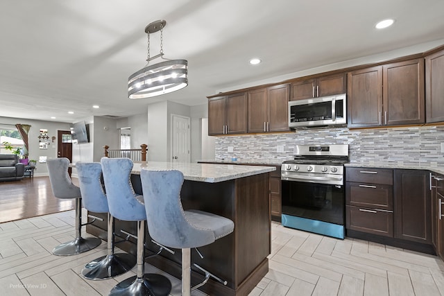 kitchen with hanging light fixtures, stainless steel fridge, tasteful backsplash, and a breakfast bar