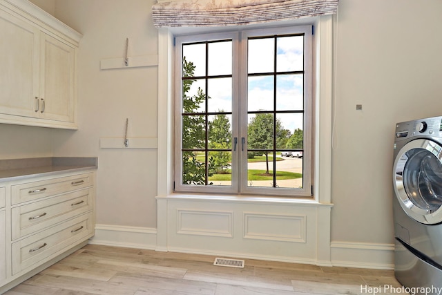 laundry room with washer / clothes dryer, plenty of natural light, cabinets, and light wood-type flooring