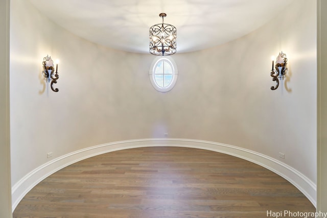 empty room featuring hardwood / wood-style floors and a chandelier