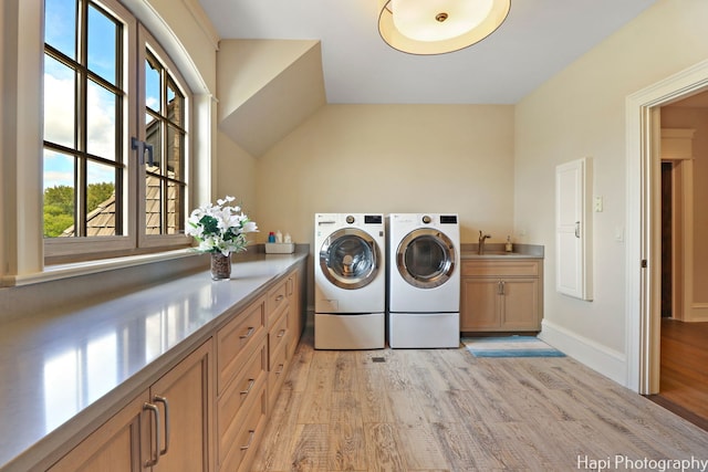 laundry room with light wood-type flooring, separate washer and dryer, cabinets, and sink