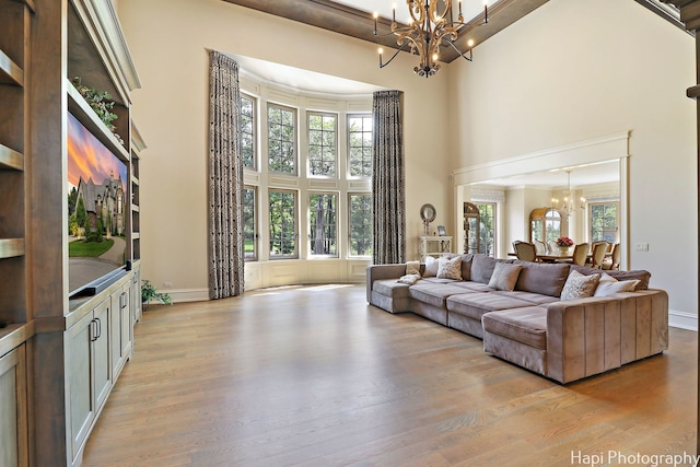 living room featuring a towering ceiling, light wood-type flooring, and a notable chandelier