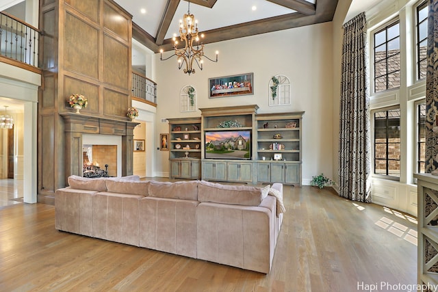 living room featuring light wood-type flooring, high vaulted ceiling, an inviting chandelier, and beam ceiling