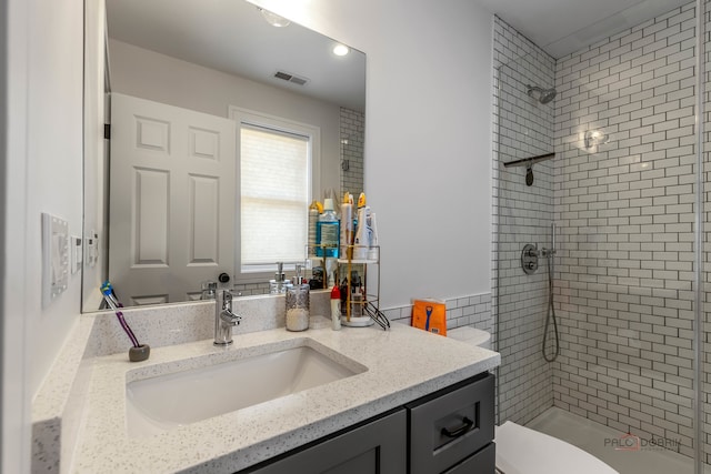 bathroom with vanity, toilet, and tiled shower