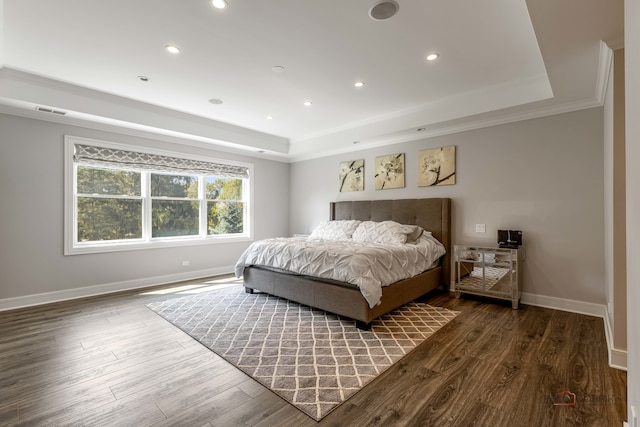 bedroom with dark hardwood / wood-style floors, a raised ceiling, and ornamental molding