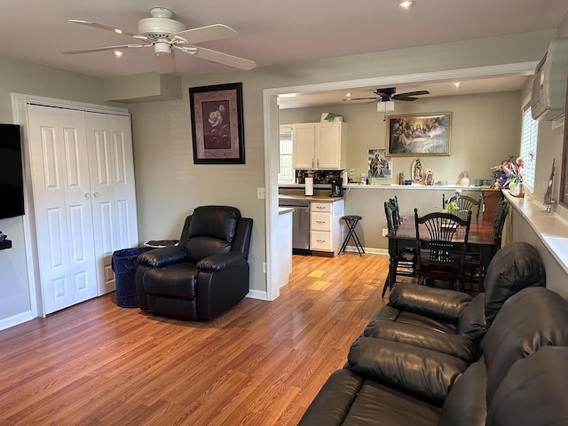 living room with baseboards, a ceiling fan, and light wood-style floors