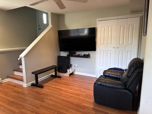 living room with ceiling fan, stairs, baseboards, and wood finished floors