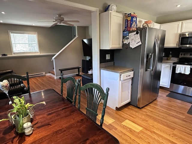 kitchen featuring stainless steel appliances, white cabinetry, light wood-style flooring, and baseboard heating