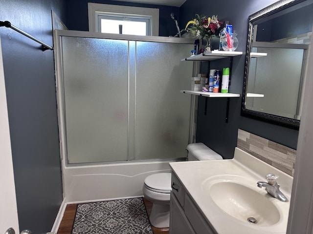 full bath featuring toilet, combined bath / shower with glass door, wood finished floors, and vanity