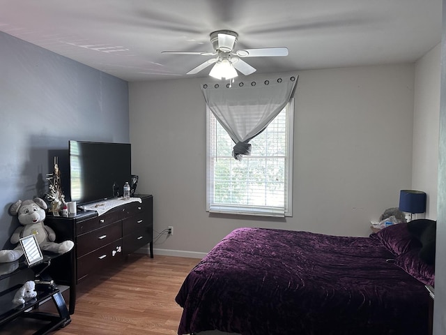 bedroom with light wood finished floors, a ceiling fan, and baseboards