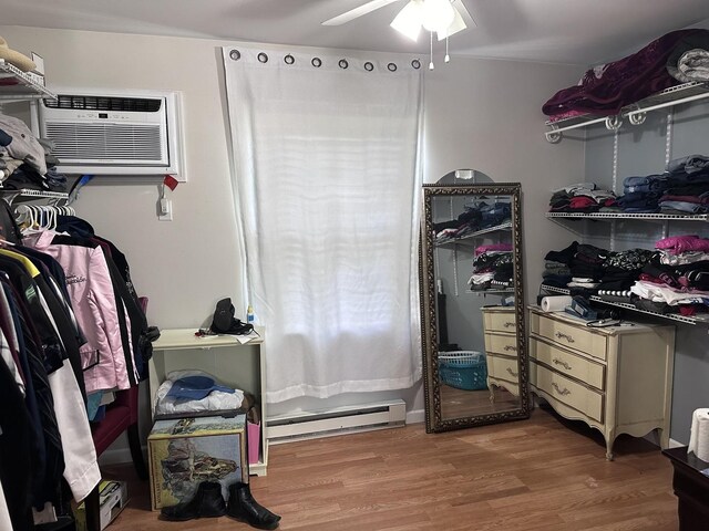 spacious closet with a baseboard heating unit, ceiling fan, hardwood / wood-style flooring, and an AC wall unit