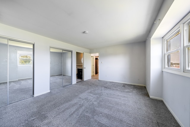 unfurnished bedroom with light colored carpet and two closets