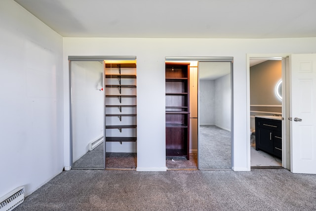 unfurnished bedroom with dark colored carpet, baseboard heating, and multiple closets