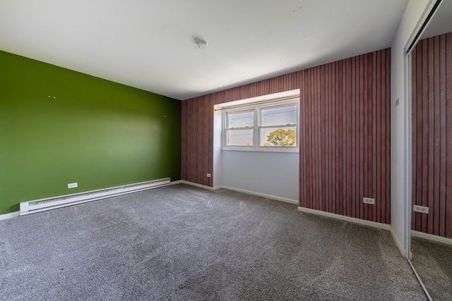 carpeted empty room featuring baseboard heating