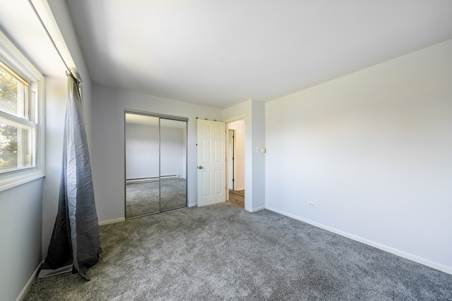 unfurnished bedroom with a baseboard heating unit, a closet, and carpet floors