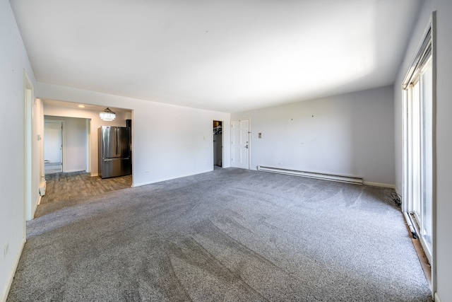 unfurnished room featuring a baseboard heating unit and carpet flooring