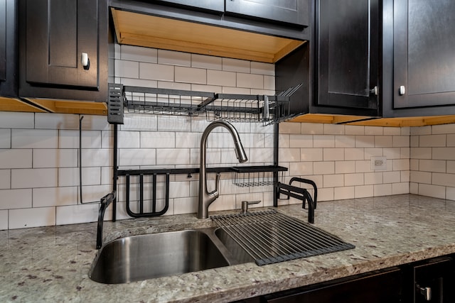 kitchen with tasteful backsplash, light stone counters, and sink