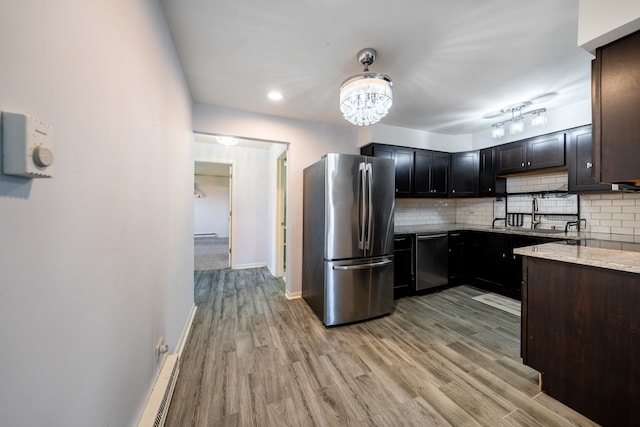 kitchen featuring a notable chandelier, light hardwood / wood-style flooring, backsplash, stainless steel appliances, and light stone countertops