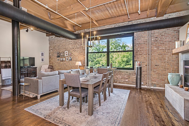 dining space with brick wall, an inviting chandelier, wooden ceiling, dark wood-type flooring, and a towering ceiling