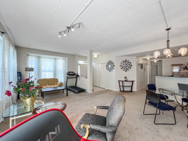 carpeted living room featuring rail lighting and a notable chandelier