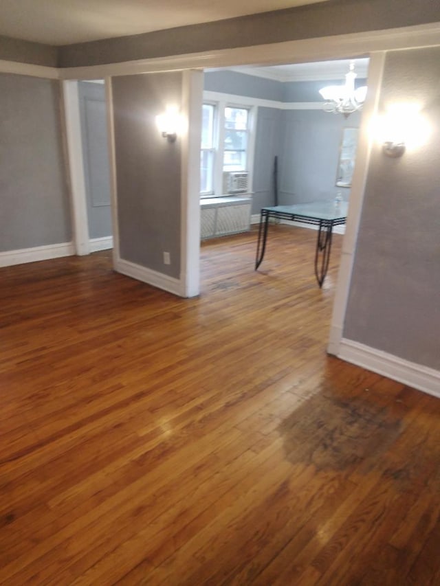 basement featuring baseboards, radiator heating unit, wood finished floors, and an inviting chandelier