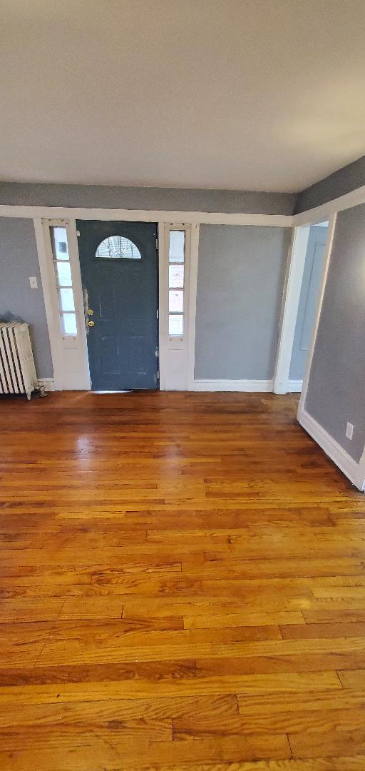 foyer entrance featuring radiator, wood finished floors, and baseboards