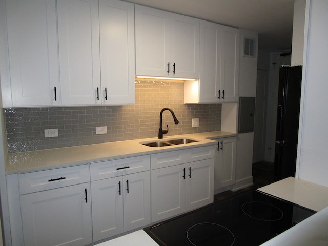 kitchen featuring sink, white cabinetry, decorative backsplash, and black cooktop