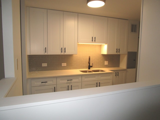 kitchen featuring sink, white cabinetry, and backsplash