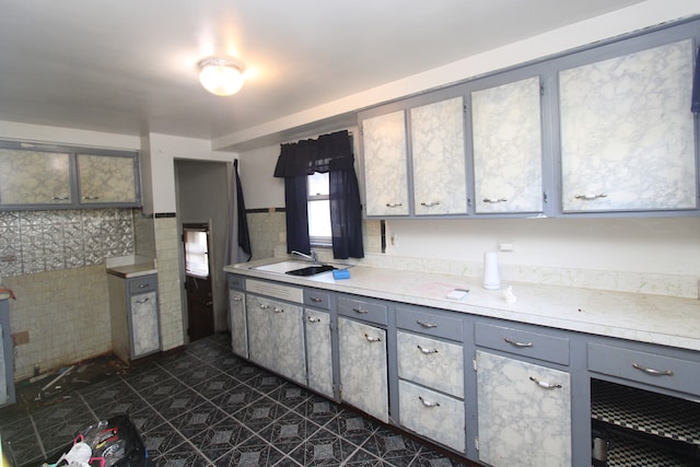 kitchen with dark tile patterned flooring, backsplash, sink, and gray cabinetry