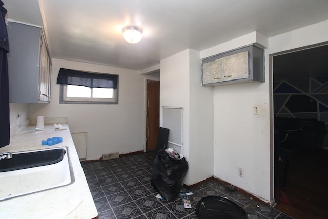 kitchen with gray cabinets, dark tile patterned floors, and sink