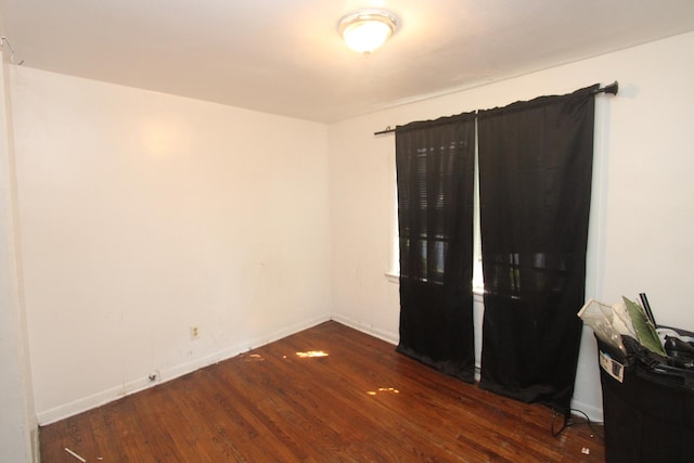 spare room with baseboards and wood finished floors